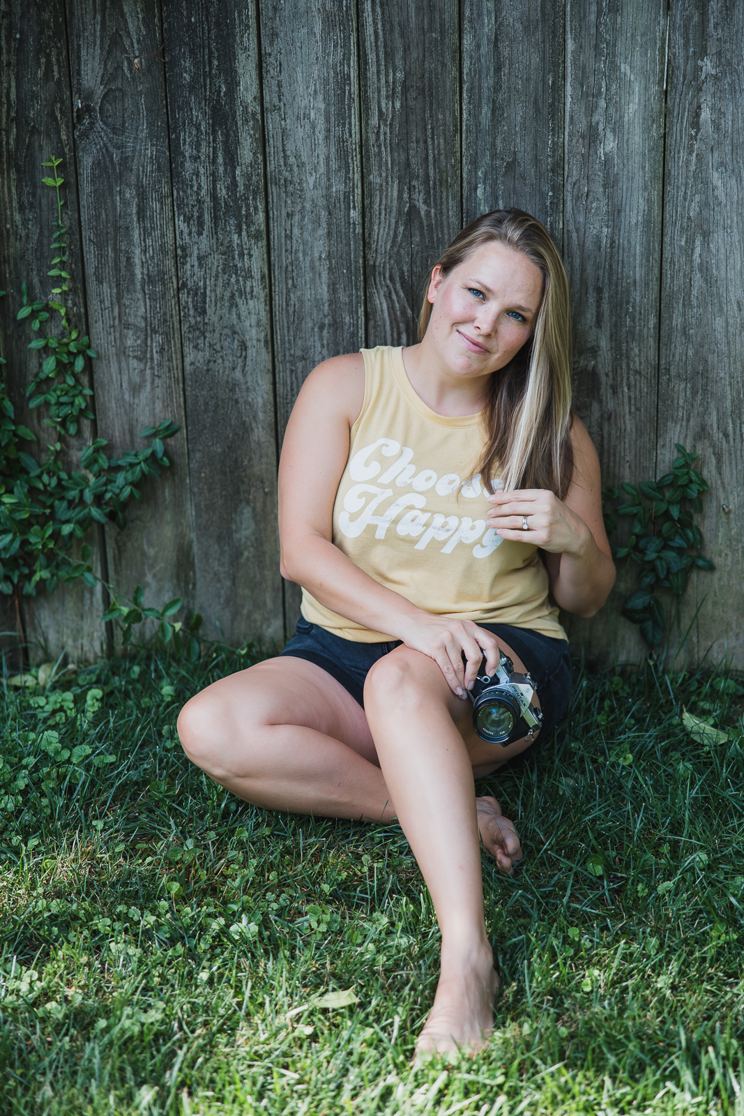 Professional headshot of Jennifer Mosier, lifestyle photographer in taken in Farmington, Missouri sitting outdoors by a wooden fence.