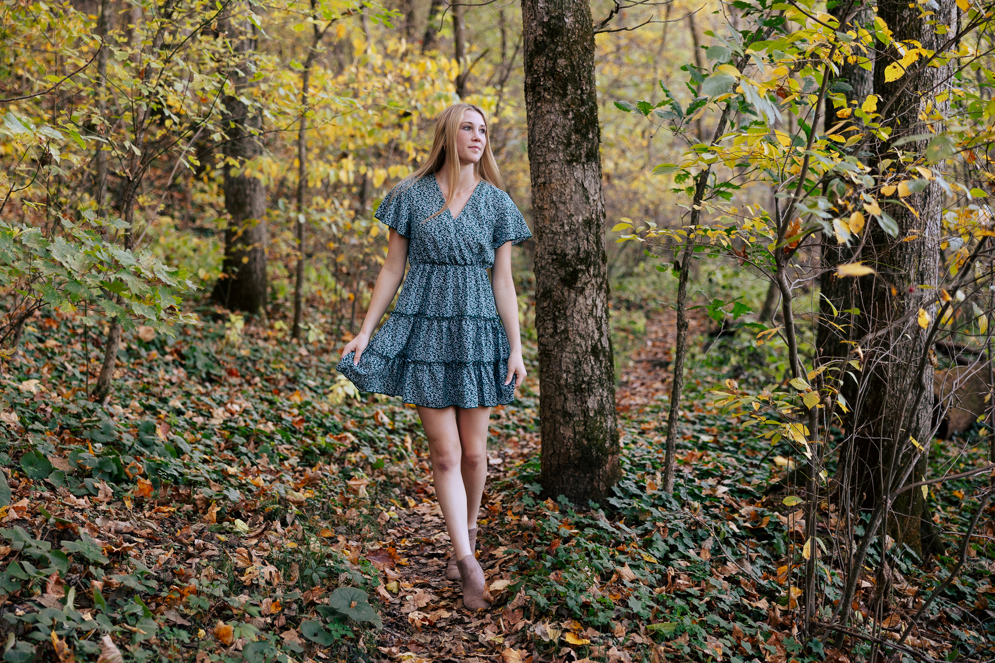 Senior girl walking through the woods during the fall in De Soto, Missouri